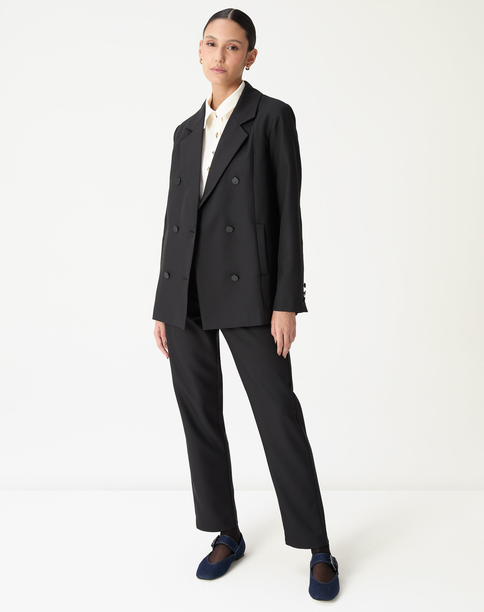 Blazer oversized preto longo em look completo visto de frente com calça reta preta e mocassim azul-marinho, imagem frontal full body.