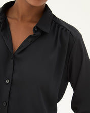 Detalhe da manga longa da camisa preta, mostrando o punho simples com botão.