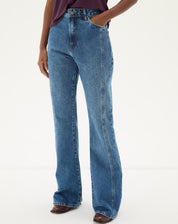 Vista frontal da calça jeans flare azul médio com blusa roxa.