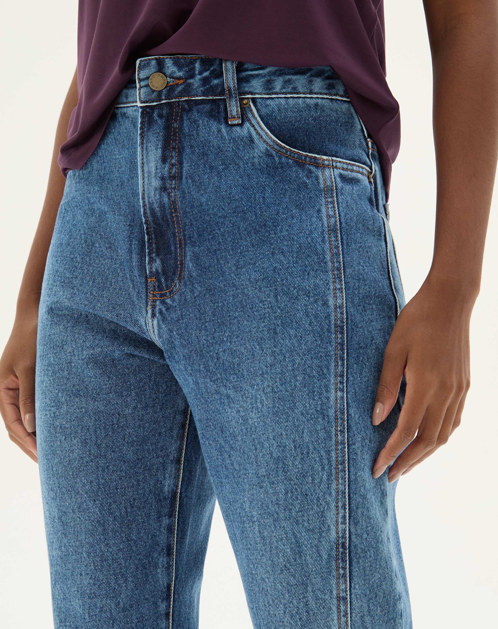 Detalhe do cós e fechamento da calça jeans azul médio.