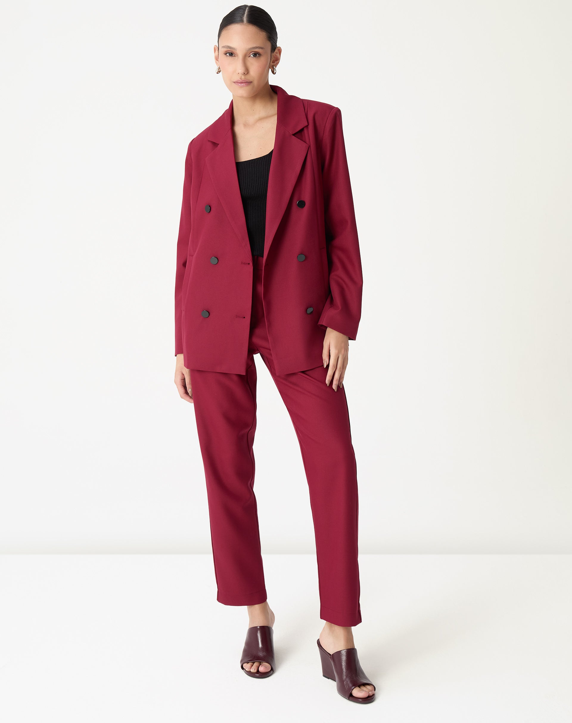 Modelo em pé vestindo blazer oversized vinho longo com calça reta combinada e top preto, visual completo frontal.