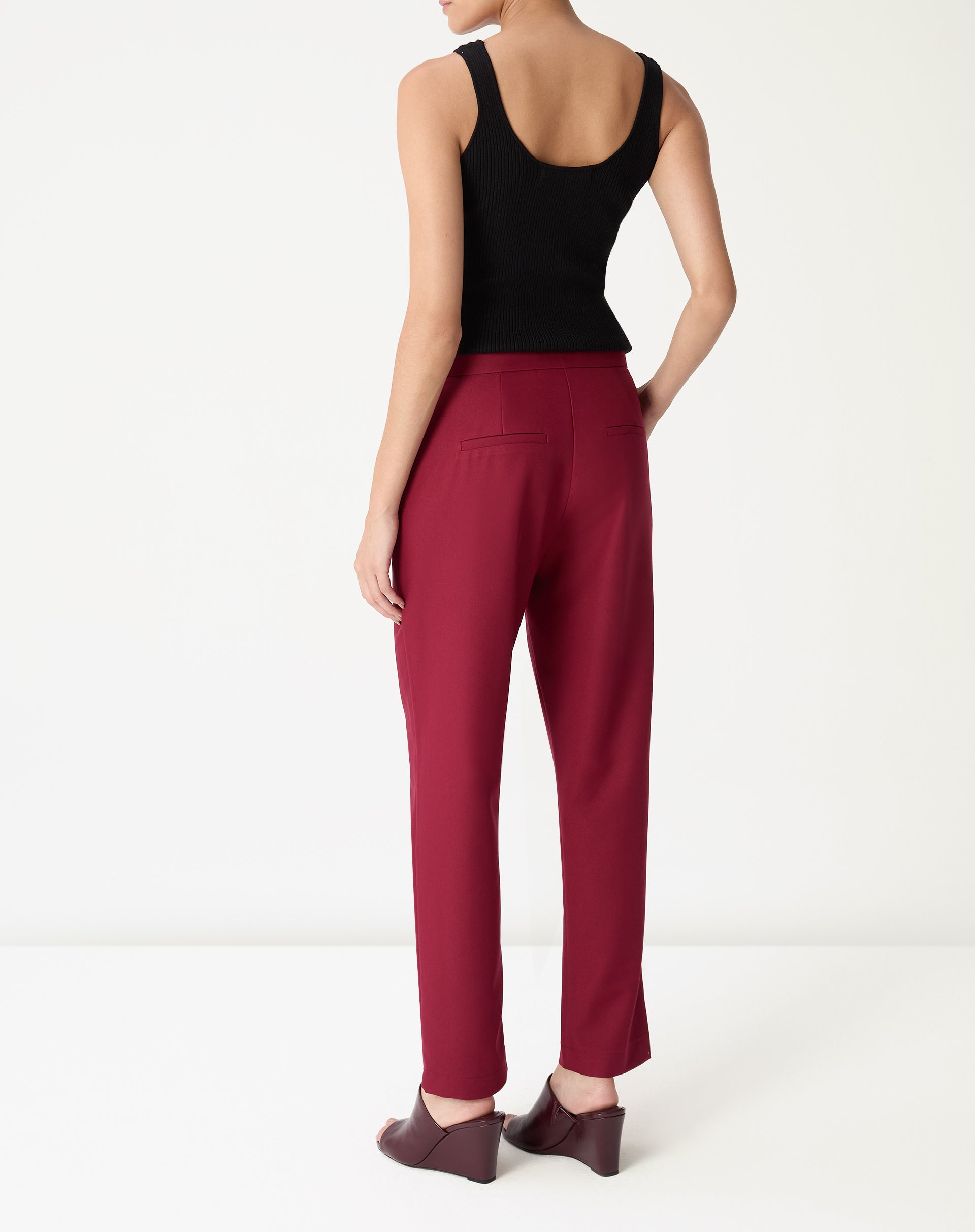 Calça slim alfaiataria vinho vista frontal em modelo com regata preta, caimento reto e comprimento longo