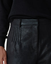 Flat lay do shorts metalizado preto com modelagem reta e bainha aplicada, destaque para o brilho discreto do tecido
