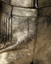 Macro da textura metálica do suedine dourado exibindo efeito envelhecido e brilho irregular