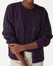 Close-up do torso de modelo usando cardigan tricot roxo com ponto diferenciado, destaque para tranças e pontos abertos.