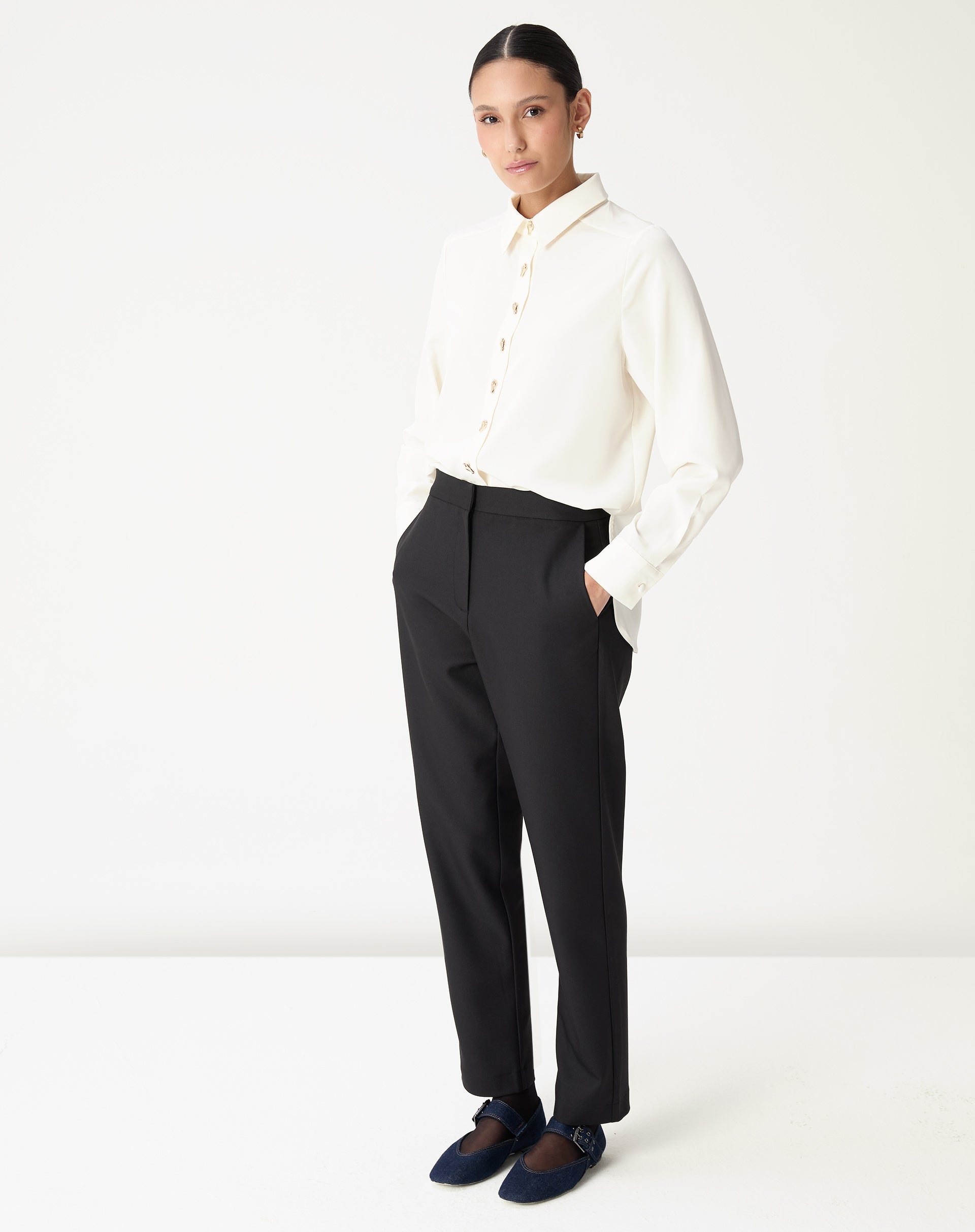 Look completo com camisa alongada off-white combinada com calça preta reta, styling formal-casual