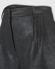 Detalhe em close do tecido suedine com acabamento metalizado do shorts preto, evidenciando textura e costuras