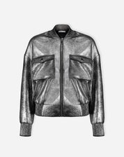 Imagem em corpo inteiro da modelo usando jaqueta bomber prata com shorts prateados e sandálias, look curto e descolado