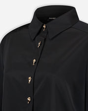 Close-up do colarinho pontudo e parte superior da camisa preta mostrando o acabamento da gola e o primeiro botão dourado