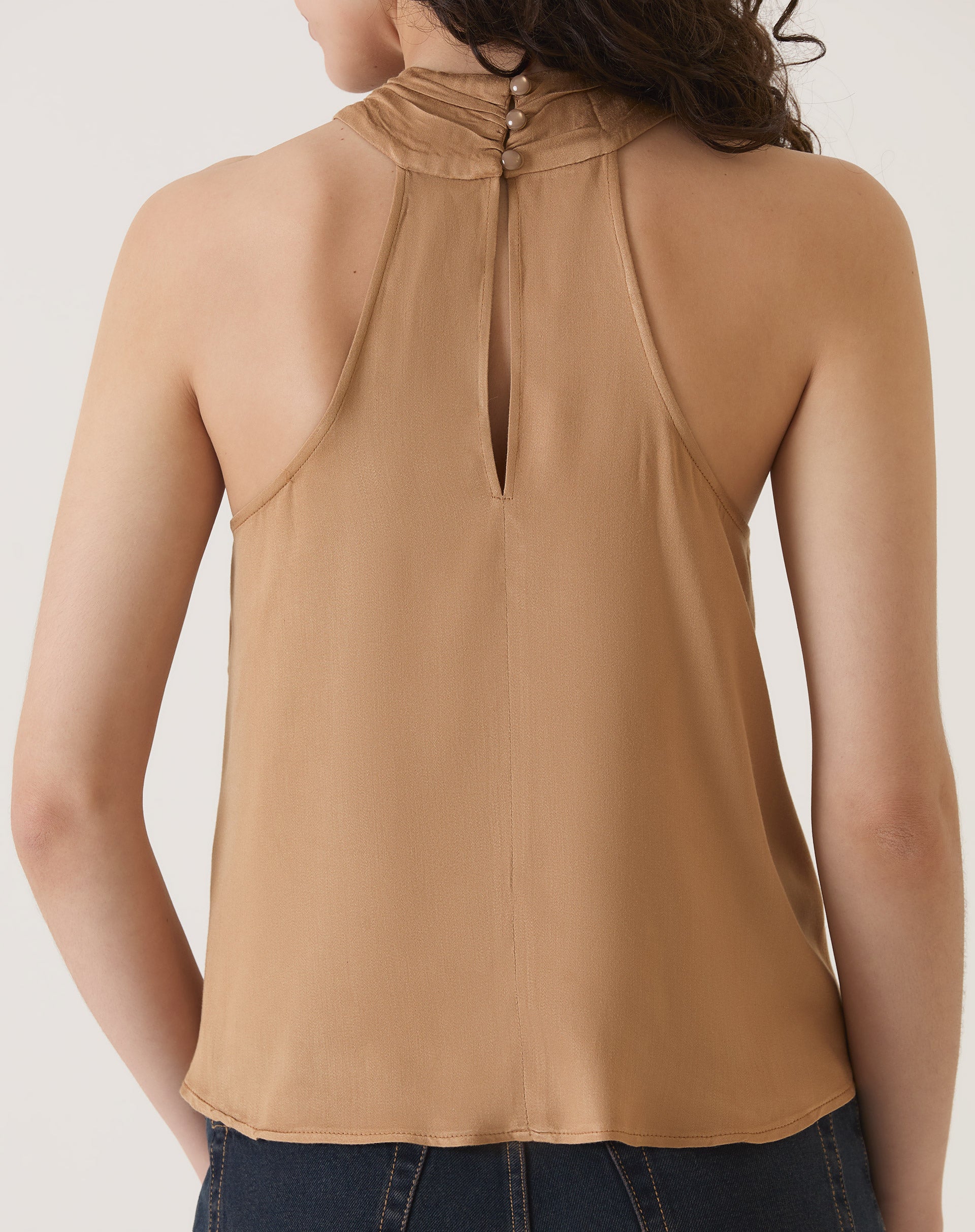 Vista traseira da blusa bege, destacando o fechamento com botões.